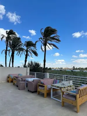 a patio with tables and chairs and palm trees at Royal Nile Suites - Nile View 1 in Luxor