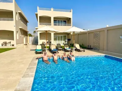 a group of men in a swimming pool in front of a house at Royal Nile Suites - Nile View 2 in Al Aqālitah