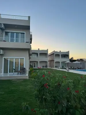 a large apartment building with a yard with red flowers at Royal Nile Suites - Luxury Nile View 1 in Al Aqālitah