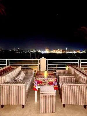 a deck with three couches and a table with a candle at Royal Nile Suites - Luxury Nile View 1 in Al Aqālitah