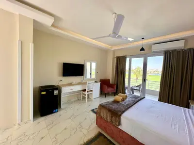 a bedroom with a bed and a desk and a television at Royal Nile Suites - Luxury Nile View 1 in Al Aqālitah