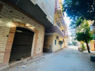 a brick building with a garage door on a street at Pharaoh apatrtment in Al Karnak
