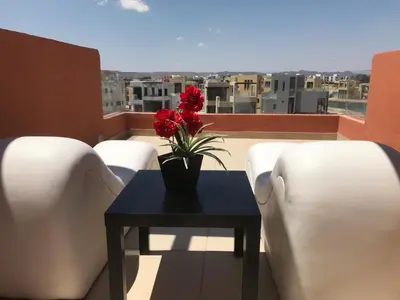 a table with a vase with red flowers on a balcony at lagoon villa in Hurghada