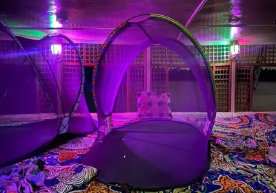 a room with purple lighting and a bed with an umbrella at The Adventures of Aga Khan in Aswan