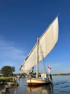 a boat with a sail in the water at The Adventures of Aga Khan in Aswan