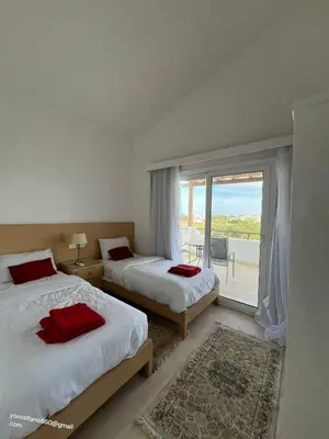 a bedroom with two beds and a large window at white villa 4 bedroom elgouna heated pool in Hurghada