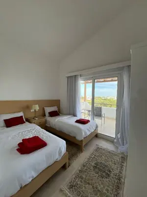 a bedroom with two beds and a large window at white villa 4 bedroom elgouna heated pool in Hurghada