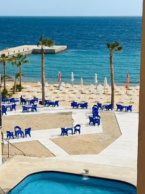 a beach with chairs and tables and the ocean at Luxurious and Cozy Seafront Studio Near Gouna in Hurghada