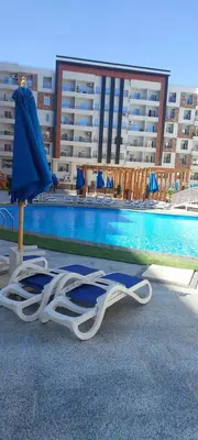two lounge chairs and an umbrella next to a swimming pool at Zahabia Golden Beach Resort Down Town in Hurghada