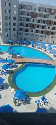 an overhead view of a large swimming pool with chairs and umbrellas at Zahabia Golden Beach Resort Down Town in Hurghada