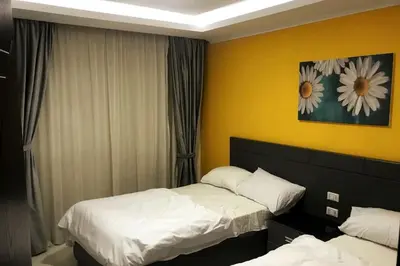 a bedroom with two beds and a painting on the wall at Cozy Studio in modern resort in Hurghada