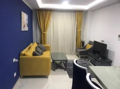 a living room with a yellow couch and a tv at Cozy Studio in modern resort in Hurghada