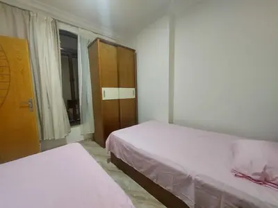 a bedroom with two beds and a cabinet and a window at Golden key in Hurghada