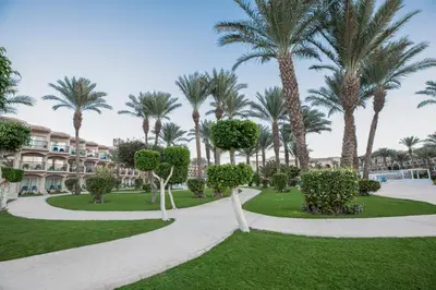 a park with palm trees and a building at Pyramisa Beach Resort Sahl Hasheesh in Hurghada