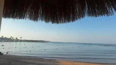 a beach with people swimming in the water at Mackdi hights in Hurghada