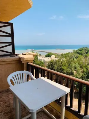a white table and chair on a balcony with the ocean at One Bedroom At Turtle Beach Compound With Private Beach in Hurghada