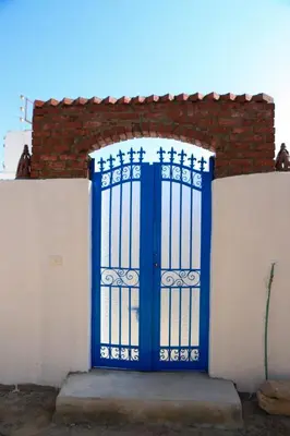 a blue door on the side of a white fence at Karma house in Luxor