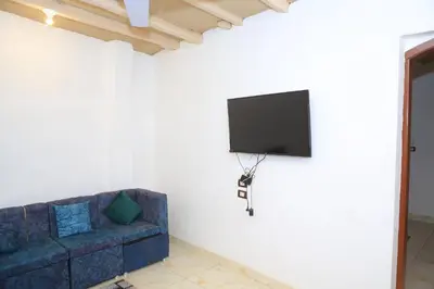a living room with a couch and a tv on a wall at Karma house in Luxor