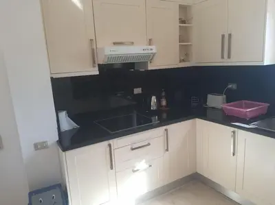 a kitchen with white cabinets and a black counter top at Villa, with heated Pool and Lagoon in Hurghada