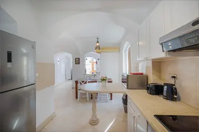 a kitchen with white cabinets and a table in it at Cozy villa with private pool in Upper Nubia in Hurghada