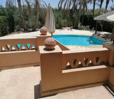 a swimming pool in a backyard with a umbrella at Cozy villa with private pool in Upper Nubia in Hurghada