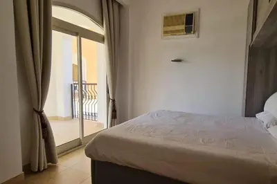 a bedroom with a bed and a door to a balcony at Nile Front Luxor Apt Sleeps 6 with Pool in Luxor