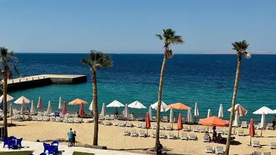 a beach with chairs and umbrellas and the ocean at Juliana beach in Hurghada