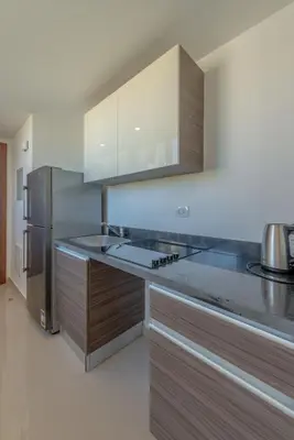 a kitchen with wooden cabinets and a stainless steel refrigerator at Peaceful 1BR studio at G-Crib El Gouna in Hurghada