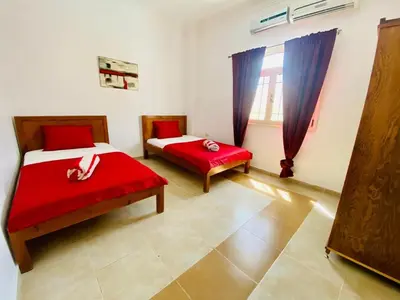 a bedroom with two beds with red sheets and a window at Hurghada-Magawish Villa 5 in Hurghada