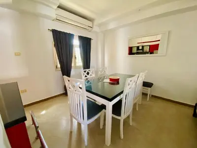 a dining room with a glass table and white chairs at Hurghada-Magawish Villa 5 in Hurghada