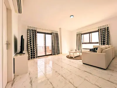 a living room with a couch and a tv and two windows at Das Nistkästchen in Hurghada in Hurghada