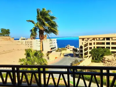 a balcony with a view of a beach and a building at The view hurghada in Hurghada