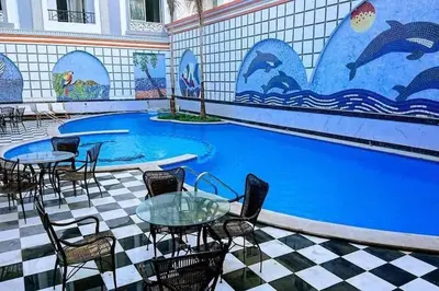 a pool with tables and chairs and a tile wall at Sheraton Plaza house near the beaches and near New Marina studio 428 in Hurghada
