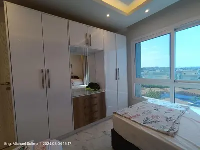 a white bedroom with a bed and a window at Fanadir sea view Appartment in Hurghada