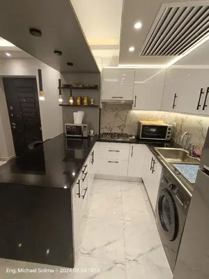 a kitchen with white cabinets and black counter tops at Fanadir sea view Appartment in Hurghada