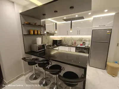 a kitchen with black counter tops and bar stools at Fanadir sea view Appartment in Hurghada