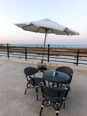 a table and chairs with an umbrella next to the beach at Studio FOR RENT IN ELWAZRA EREA BEFOR EL GOUNA 5 MINUTES ONE BEDROOM in Hurghada