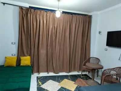 a living room with a green couch and a window at Studio FOR RENT IN ELWAZRA EREA BEFOR EL GOUNA 5 MINUTES ONE BEDROOM in Hurghada