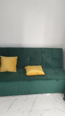 a green couch with two yellow pillows on it at Studio FOR RENT IN ELWAZRA EREA BEFOR EL GOUNA 5 MINUTES ONE BEDROOM in Hurghada