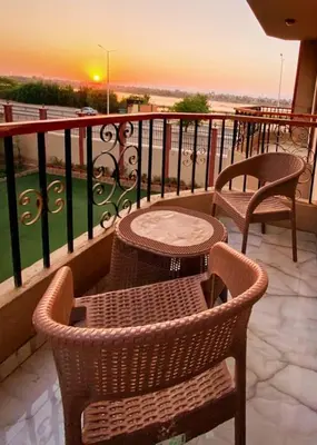 a balcony with two chairs and a table on a balcony at Luxor family apartment in Luxor