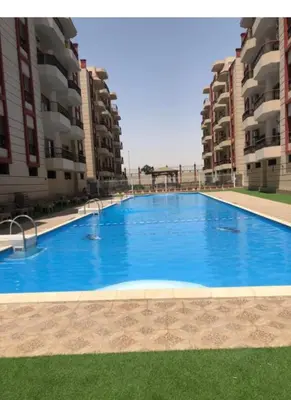 a large blue swimming pool in front of two apartment buildings at Luxor family apartment in Luxor