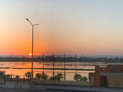 a sunset over a body of water with a street light at Luxor Apparment in Al Bayāḑīyah