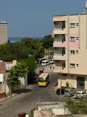 a yellow van parked in a parking lot next to a building at Apartment all yours in Hurghada
