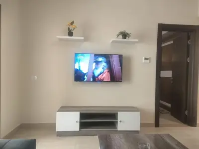 a living room with a tv on a white wall at Diamond Lily Aldau heights Hurghada rent one bedroom apartment in Hurghada
