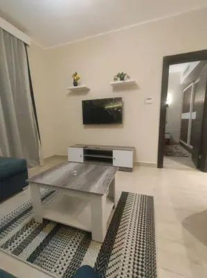 a living room with a table and a tv at Diamond Lily Aldau heights Hurghada rent one bedroom apartment in Hurghada
