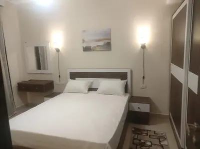 a bedroom with a large white bed with two lamps at Diamond Lily Aldau heights Hurghada rent one bedroom apartment in Hurghada