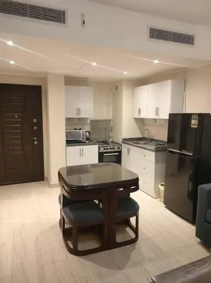a kitchen with a table and a black refrigerator at Diamond Lily Aldau heights Hurghada rent one bedroom apartment in Hurghada