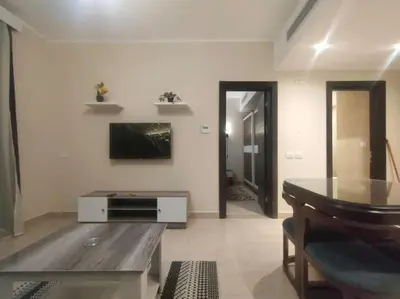 a living room with a table and a television at Diamond Lily Aldau heights Hurghada rent one bedroom apartment in Hurghada