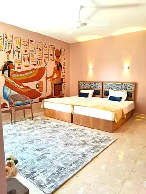a bedroom with two beds and a rug at Magic Quest Retreat 10 min von Aswan in Nag` el-Fuqâhi
