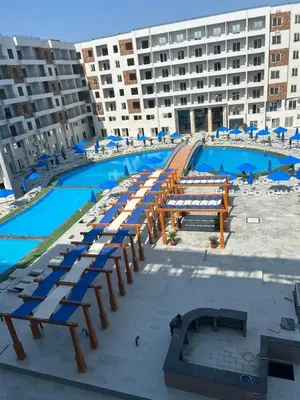 a large pool with lounge chairs and a large building at Tiba gollden resort in Hurghada